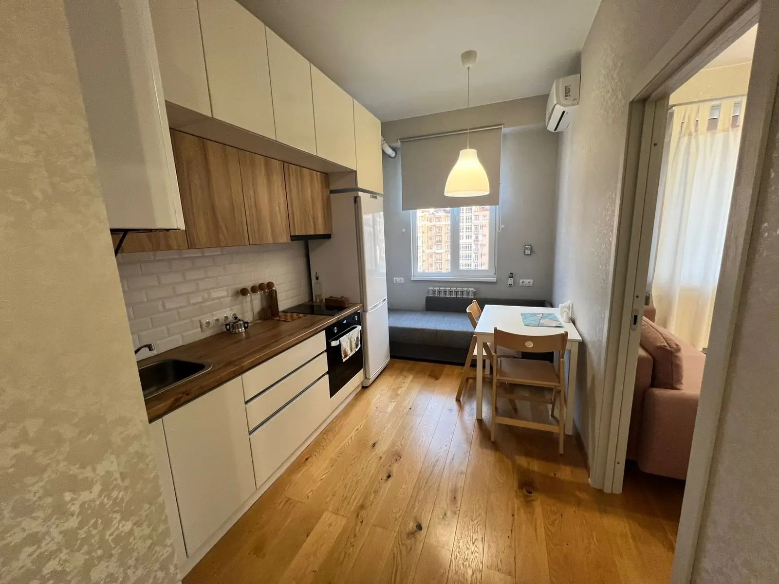 Квартира-студия с современным кухонным гарнитуром и деревянным полом